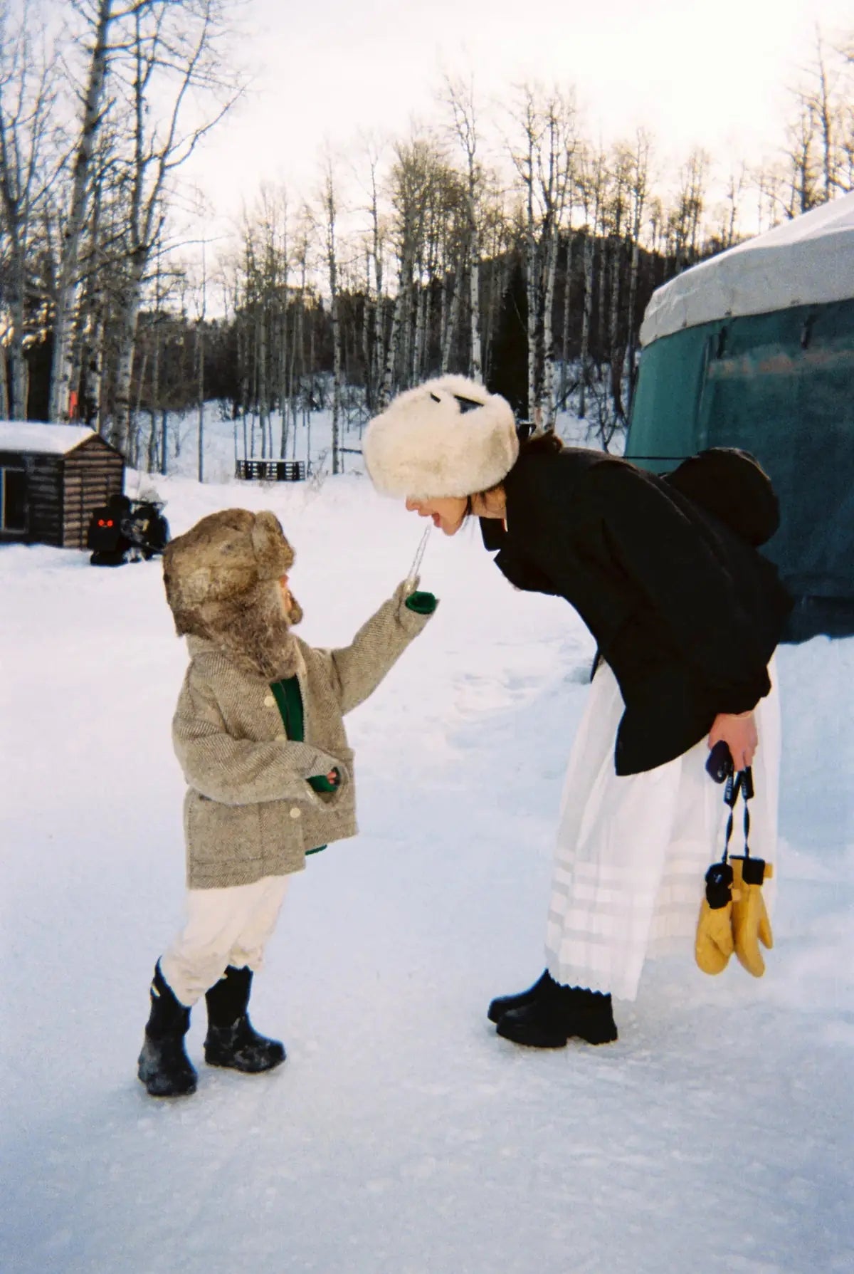 A toddler and her mother playing in the snow